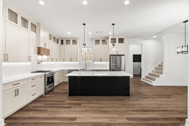 kitchen with recessed lighting, stainless steel appliances, dark wood-type flooring, under cabinet range hood, and a center island