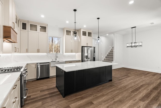 kitchen featuring a sink, tasteful backsplash, a kitchen island, appliances with stainless steel finishes, and dark wood-style flooring