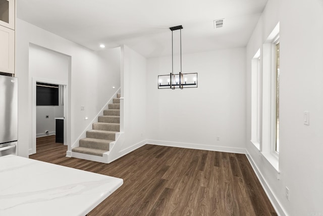 unfurnished dining area with visible vents, baseboards, stairs, dark wood-style floors, and a notable chandelier