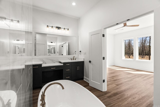 full bath with wood finished floors, baseboards, a soaking tub, ceiling fan, and vanity