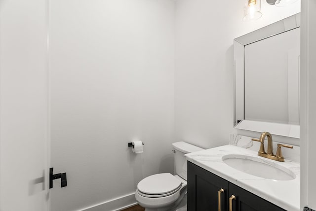 half bath with vanity, toilet, and baseboards