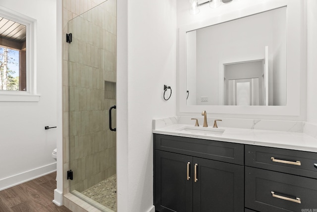 bathroom with a stall shower, vanity, baseboards, and wood finished floors