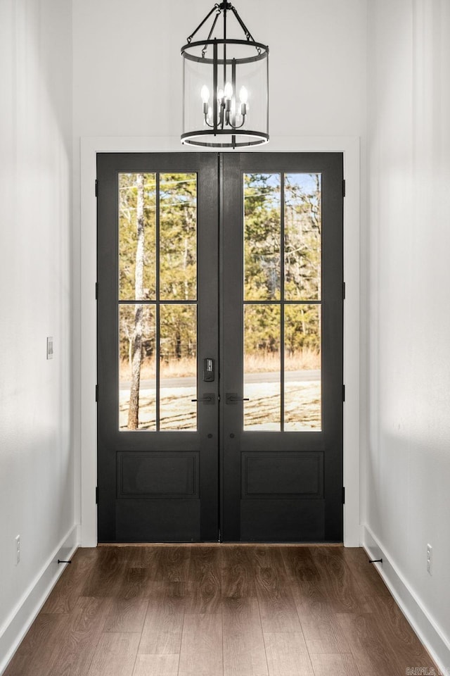 doorway with french doors, baseboards, an inviting chandelier, and dark wood-style floors