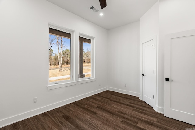 spare room with visible vents, baseboards, and dark wood-style flooring