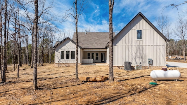 back of house featuring central AC unit, roof with shingles, and board and batten siding