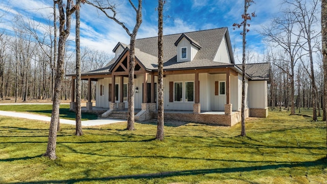 view of front of home featuring covered porch, board and batten siding, a front yard, and a shingled roof