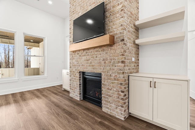 unfurnished living room featuring recessed lighting, baseboards, a fireplace, and dark wood-style flooring