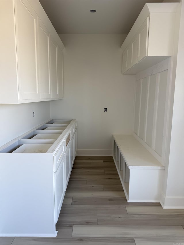 laundry area with light wood-style flooring and baseboards