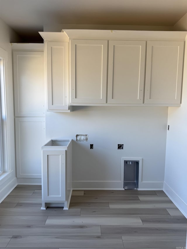 laundry area featuring light wood finished floors, cabinet space, electric dryer hookup, and baseboards