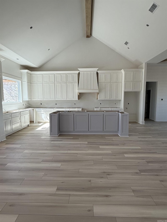 kitchen with beamed ceiling, light wood-style floors, visible vents, and high vaulted ceiling