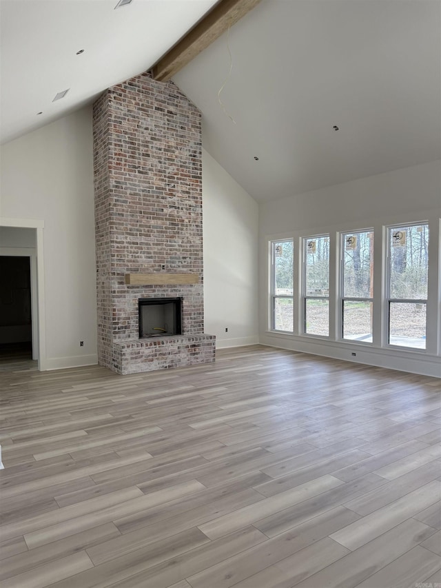 unfurnished living room featuring a brick fireplace, beamed ceiling, high vaulted ceiling, and light wood-type flooring