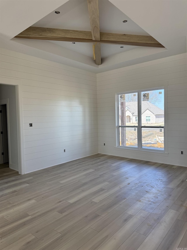 spare room with a tray ceiling and light wood-style flooring