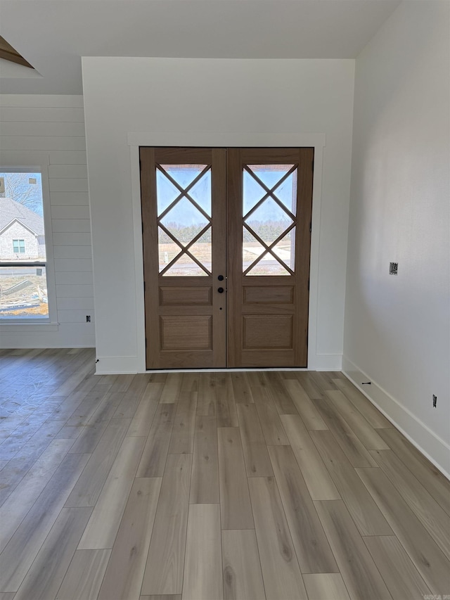 entrance foyer with light wood-style flooring, french doors, and baseboards