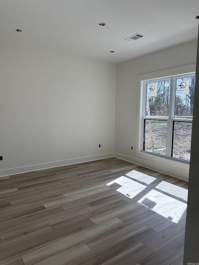 empty room with visible vents, baseboards, and wood finished floors