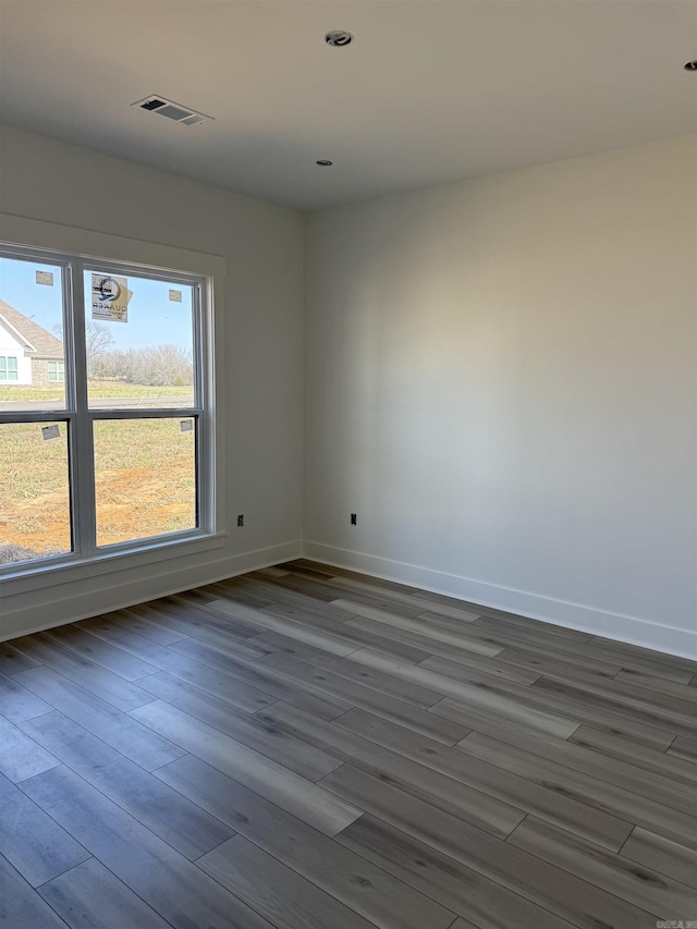 unfurnished room with visible vents, baseboards, and dark wood-style flooring