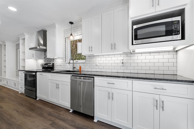 kitchen featuring dark wood finished floors, stainless steel appliances, white cabinetry, wall chimney exhaust hood, and a sink