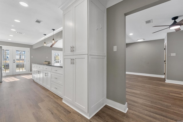 kitchen with visible vents, wood finished floors, white cabinetry, french doors, and baseboards