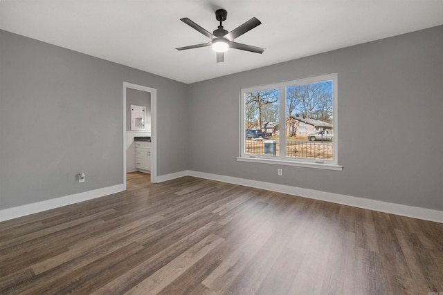 spare room featuring dark wood finished floors, a ceiling fan, and baseboards