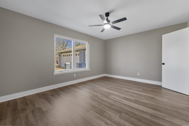 spare room featuring baseboards, wood finished floors, and a ceiling fan