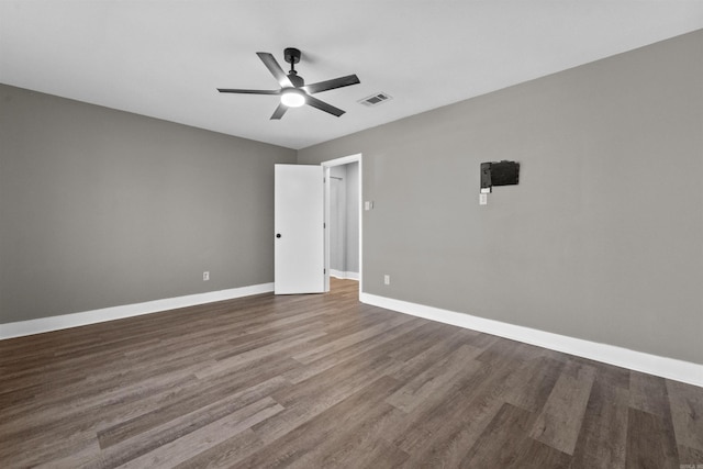 spare room with a ceiling fan, visible vents, wood finished floors, and baseboards