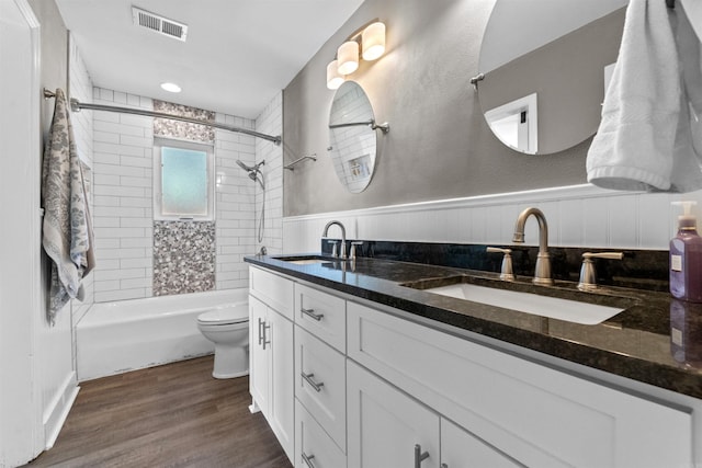 bathroom with wood finished floors, visible vents, a wainscoted wall, and a sink