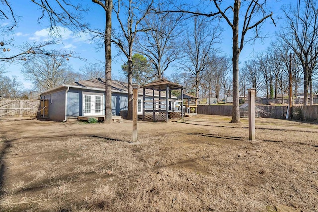 rear view of house with french doors, brick siding, a wooden deck, and fence