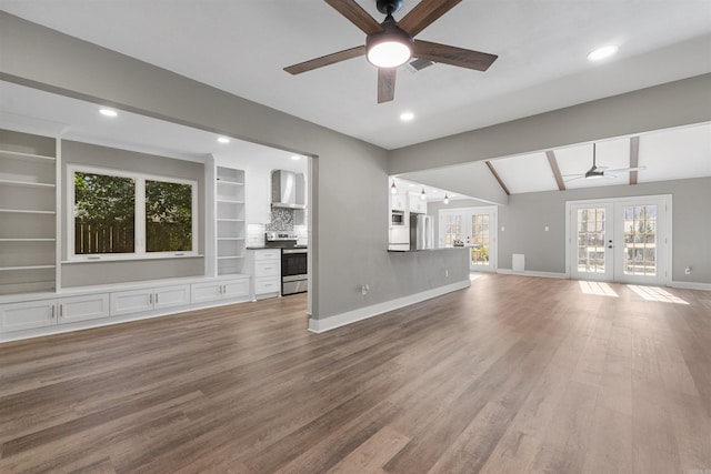 unfurnished living room featuring baseboards, lofted ceiling with beams, french doors, wood finished floors, and a ceiling fan