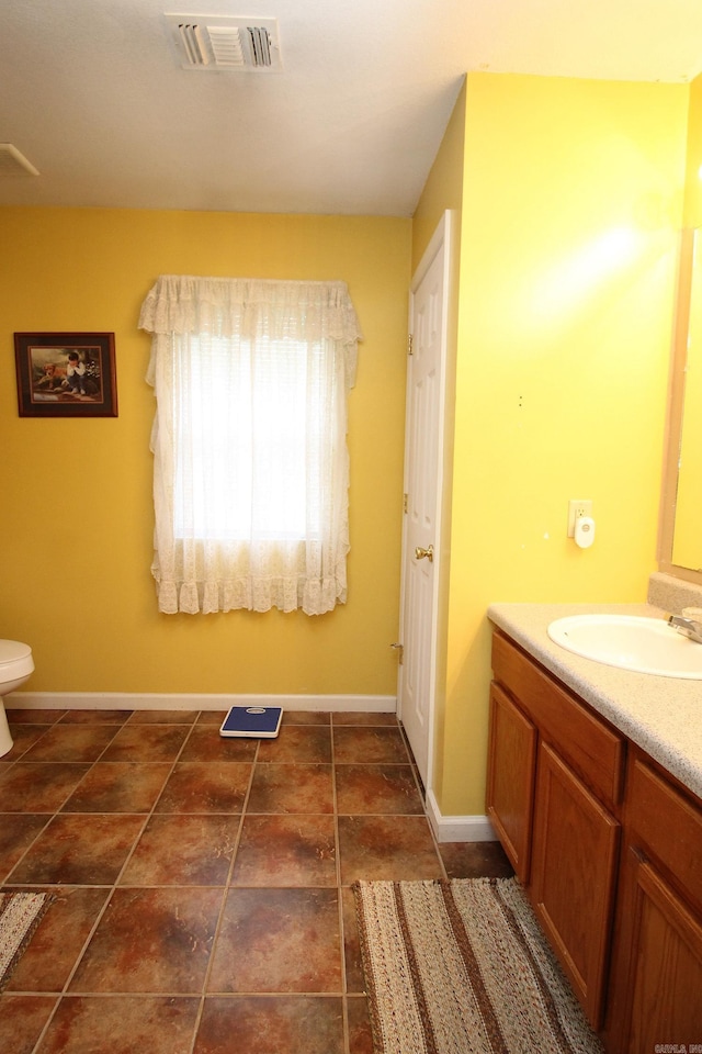 bathroom with vanity, toilet, baseboards, and visible vents