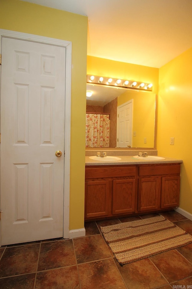 bathroom with a sink, baseboards, and double vanity