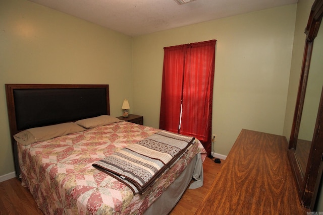 bedroom featuring visible vents, baseboards, and wood finished floors