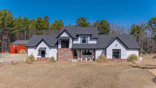 modern farmhouse with brick siding and a shingled roof