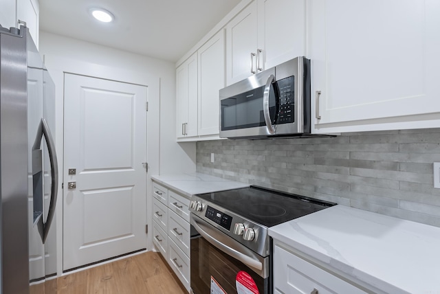 kitchen with light stone countertops, decorative backsplash, light wood-style floors, appliances with stainless steel finishes, and white cabinetry