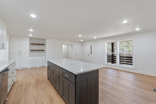 kitchen featuring white cabinetry, a kitchen island, open shelves, light wood-style flooring, and stainless steel dishwasher