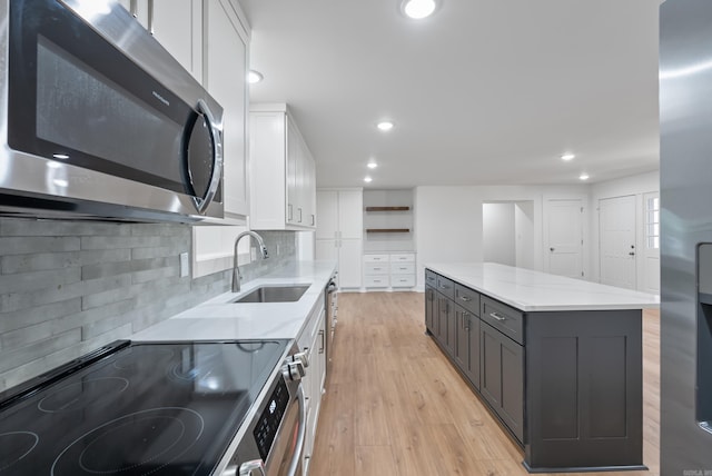 kitchen featuring a sink, gray cabinetry, appliances with stainless steel finishes, white cabinets, and open shelves