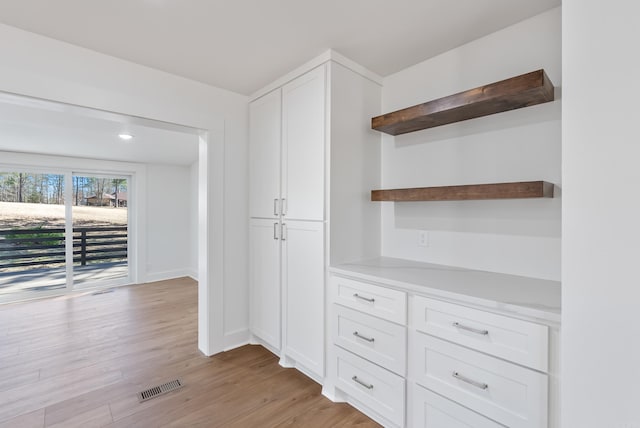 interior space with light wood finished floors, visible vents, and baseboards