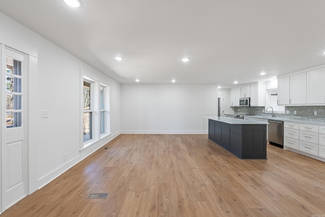 kitchen with tasteful backsplash, light countertops, white cabinets, stainless steel appliances, and a sink