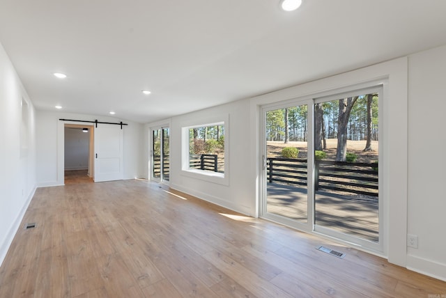 unfurnished room featuring visible vents, recessed lighting, light wood-style floors, and a barn door