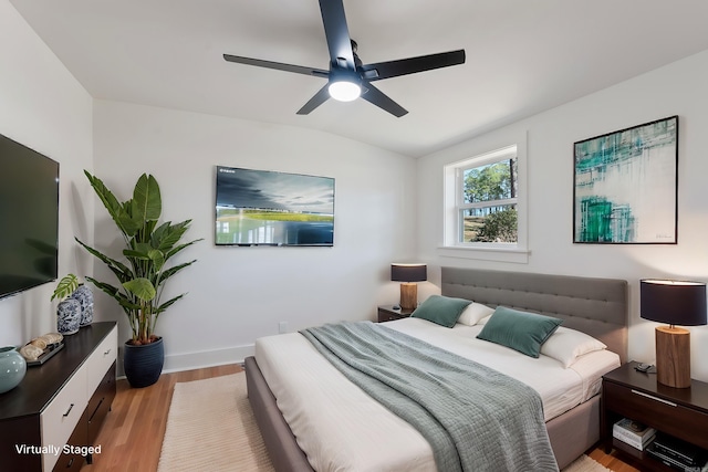 bedroom with baseboards, light wood-style floors, lofted ceiling, and ceiling fan