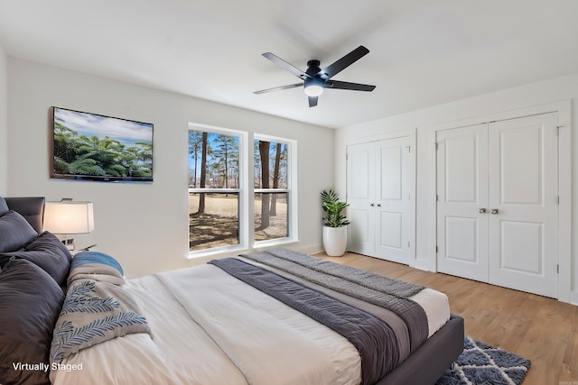 bedroom with ceiling fan, light wood-type flooring, and multiple closets