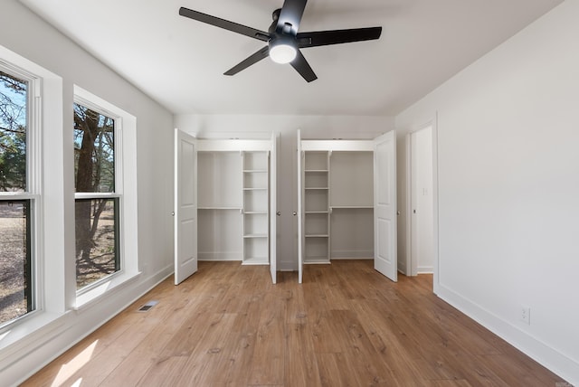 unfurnished bedroom featuring multiple windows, multiple closets, baseboards, and light wood-style flooring