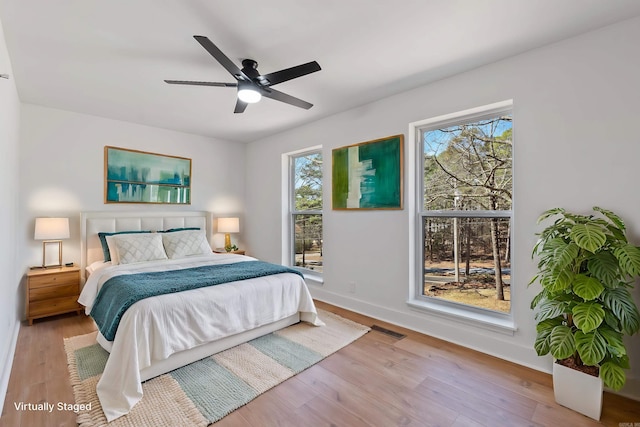 bedroom featuring visible vents, multiple windows, baseboards, and wood finished floors