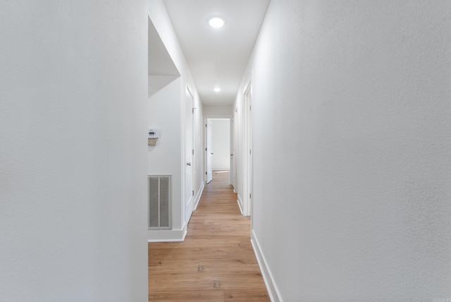 hall featuring light wood-type flooring, visible vents, baseboards, and recessed lighting