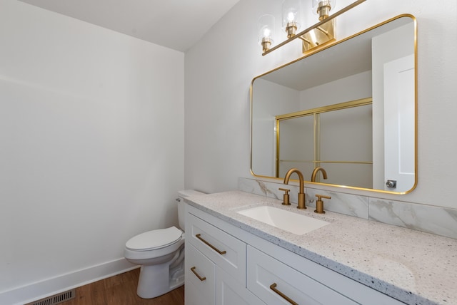 bathroom with visible vents, toilet, wood finished floors, an enclosed shower, and vanity