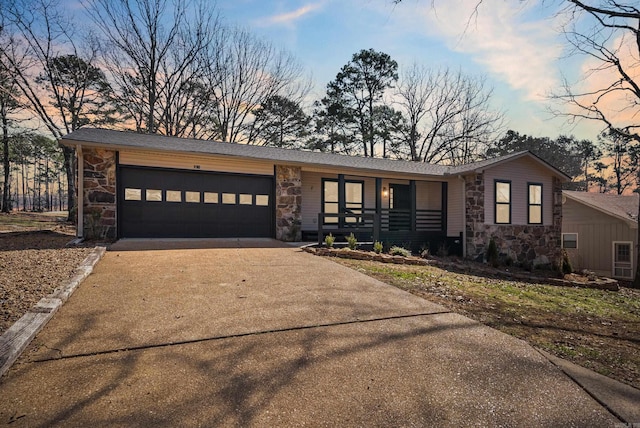 view of front of house with a garage, stone siding, and driveway