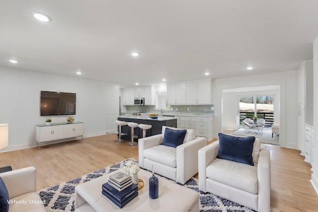 living area with recessed lighting, light wood-type flooring, and baseboards