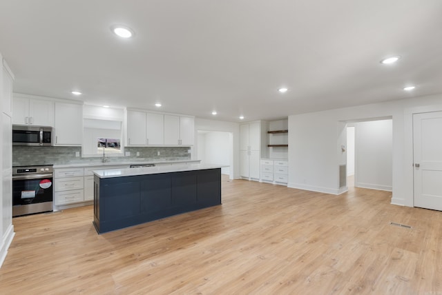 kitchen with decorative backsplash, white cabinetry, stainless steel appliances, and light countertops