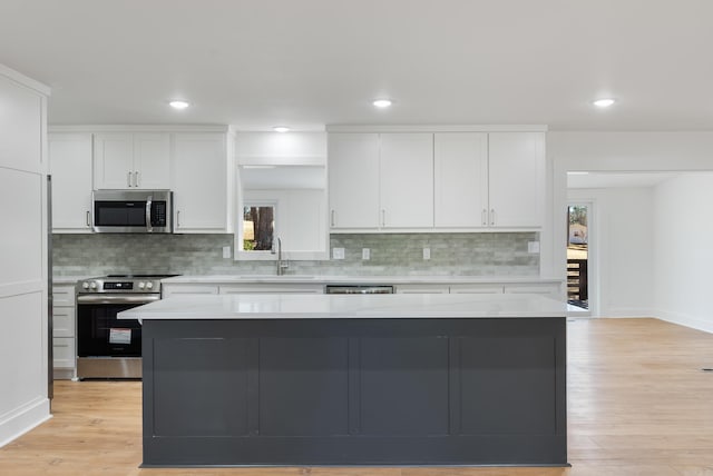 kitchen featuring a sink, appliances with stainless steel finishes, white cabinets, and light countertops