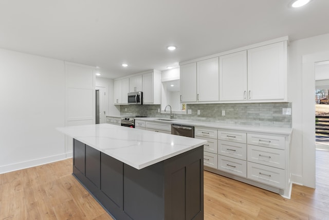 kitchen with white cabinetry, light wood-style floors, appliances with stainless steel finishes, and a sink