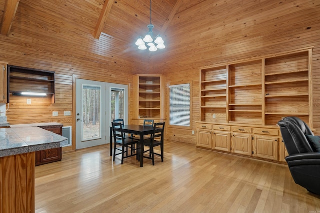 dining space with light wood-type flooring, wooden walls, wooden ceiling, and high vaulted ceiling