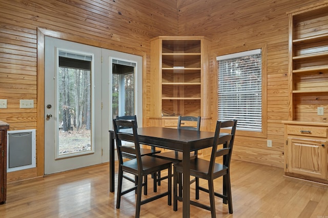 dining space with light wood-type flooring and wood walls